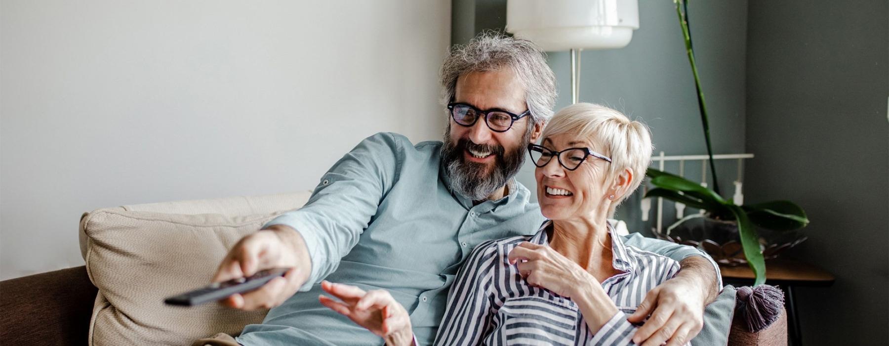 a man and a woman sitting on a couch watching TV