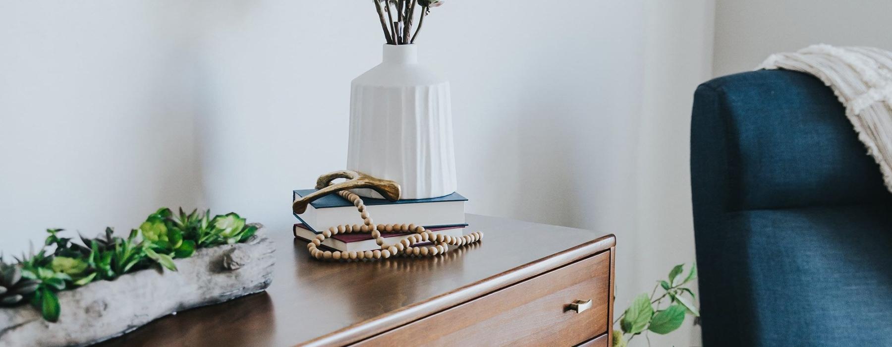 a dresser with a vase of plants on top