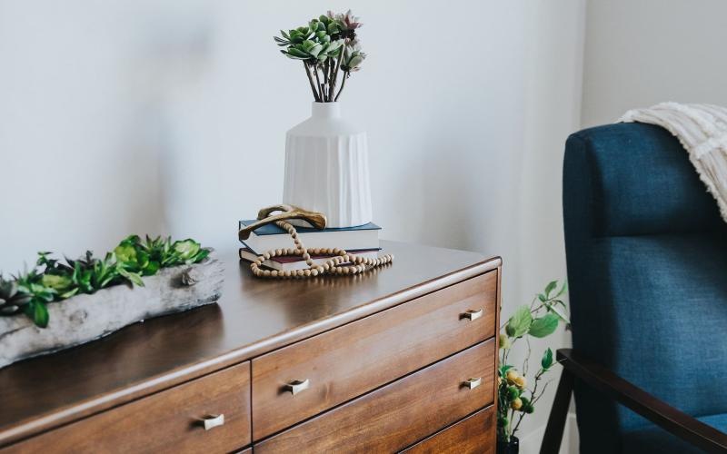 a dresser with a vase of plants on top