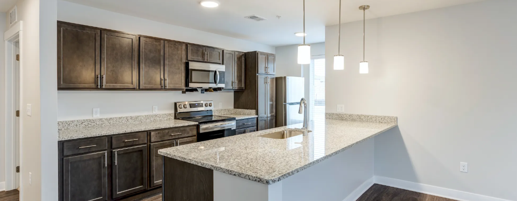 Apartment kitchen with brown cabinets and granite countertops